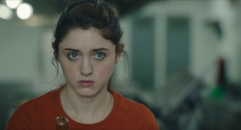 Movie still from “Yes, God, Yes” (2019), directed by Karen Maine – A woman in an orange shirt is looking at the camera; Close Up shot, Over the shoulder angle