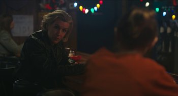 Movie still from “Yes, God, Yes” (2019), directed by Karen Maine – A woman sitting at a table with a drink in front of her; Close Up shot, Over the shoulder angle