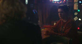 Movie still from “Yes, God, Yes” (2019), directed by Karen Maine – A man sitting at a table in front of another man; Medium shot, Over the shoulder angle
