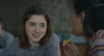 Movie still from “Yes, God, Yes” (2019), directed by Karen Maine – A woman sitting next to another woman holding a piece of food; Close Up shot, Over the shoulder angle