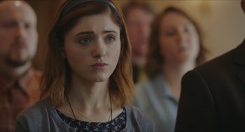 Movie still from “Yes, God, Yes” (2019), directed by Karen Maine – A woman with a headband is looking at the camera; Close Up shot, Over the shoulder angle