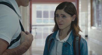 Movie still from “Yes, God, Yes” (2019), directed by Karen Maine – A woman in a white shirt and blue jean jacket looking at a man in a white shirt and blue jean jacket; Close Up shot, Over the shoulder angle
