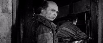 Movie still from “Yojimbo” (1961), directed by Akira Kurosawa – An older man wearing a plaid shirt and a plaid jacket; Close Up shot, Low angle