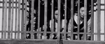 Movie still from “Yojimbo” (1961), directed by Akira Kurosawa – A group of people standing behind a wooden fence; Medium shot, Low angle