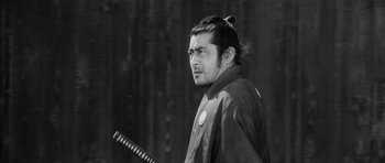 Movie still from “Yojimbo” (1961), directed by Akira Kurosawa – Black and white photograph of a man with a samurai sword; Close Up shot, Low angle