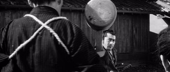 Movie still from “Yojimbo” (1961), directed by Akira Kurosawa – Two men in traditional garb are playing frisbee; Medium shot, Over the shoulder angle