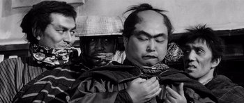 Movie still from “Yojimbo” (1961), directed by Akira Kurosawa – A group of men standing next to each other; Close Up shot, Over the shoulder angle
