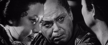 Movie still from “Yojimbo” (1961), directed by Akira Kurosawa – A black - and - white photo of a man and a woman; Close Up shot, Over the shoulder angle