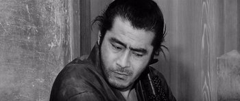 Movie still from “Yojimbo” (1961), directed by Akira Kurosawa – Black and white photograph of a man holding a cell phone to his ear; Close Up shot, Low angle