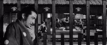 Movie still from “Yojimbo” (1961), directed by Akira Kurosawa – Black and white photograph of people sitting and standing in front of a building; Medium shot, Over the shoulder angle