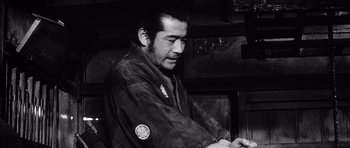 Movie still from “Yojimbo” (1961), directed by Akira Kurosawa – Black and white photograph of a man in a kimono; Medium shot, Low angle