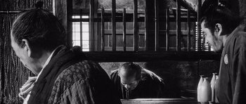 Movie still from “Yojimbo” (1961), directed by Akira Kurosawa – An old man leaning against a wall looking down at the floor; Medium shot, Low angle