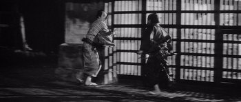 Movie still from “Yojimbo” (1961), directed by Akira Kurosawa – Two men in traditional japanese garb are fighting; Wide shot, Low angle