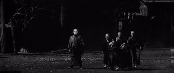 Movie still from “Yojimbo” (1961), directed by Akira Kurosawa – A group of people standing in the dark; Wide shot, Low angle