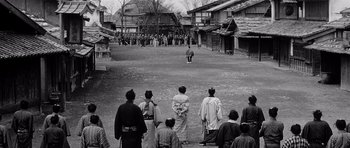 Movie still from “Yojimbo” (1961), directed by Akira Kurosawa – A group of people standing in the middle of a street; Extreme Wide shot, Over the shoulder angle