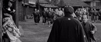 Movie still from “Yojimbo” (1961), directed by Akira Kurosawa – A black and white photo of a group of men in traditional garb; Medium shot, Over the shoulder angle