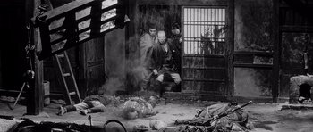 Movie still from “Yojimbo” (1961), directed by Akira Kurosawa – Two men standing in front of an open door of a building; Wide shot, High angle