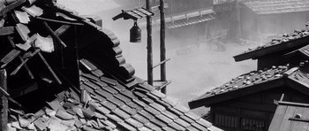 Movie still from “Yojimbo” (1961), directed by Akira Kurosawa – An image of a bell hanging on a pole in the rain; Wide shot, Low angle