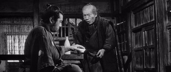 Movie still from “Yojimbo” (1961), directed by Akira Kurosawa – A man in a kimono is holding a bottle of sake and another man in a kimono is holding a bottle of sake; Medium shot, Over the shoulder angle