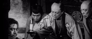 Movie still from “Yojimbo” (1961), directed by Akira Kurosawa – A man and a woman sitting next to each other holding a candle; Medium shot, Low angle