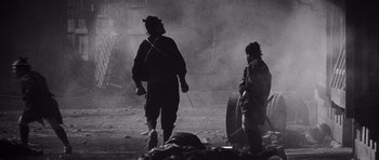Movie still from “Yojimbo” (1961), directed by Akira Kurosawa – Two men are standing in the middle of a dusty field; Wide shot, Over the shoulder angle