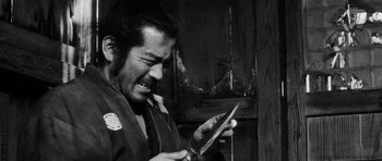 Movie still from “Yojimbo” (1961), directed by Akira Kurosawa – A man holding a pair of scissors in his hand; Close Up shot, Over the shoulder angle