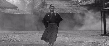 Movie still from “Yojimbo” (1961), directed by Akira Kurosawa – A man in a traditional japanese outfit walking on a dirt field; Wide shot, Low angle