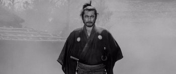 Movie still from “Yojimbo” (1961), directed by Akira Kurosawa – A black and white photo of a man in a samurai outfit; Medium shot, Low angle