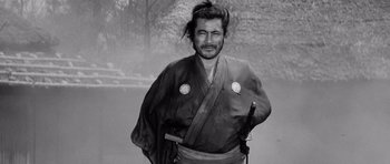 Movie still from “Yojimbo” (1961), directed by Akira Kurosawa – A man in a kimono is holding a katana; Medium shot, Low angle
