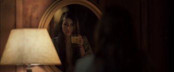 Movie still from “You're Next” (2011), directed by Adam Wingard – A woman holding a glass of orange juice in front of a mirror; Close Up shot, Over the shoulder angle