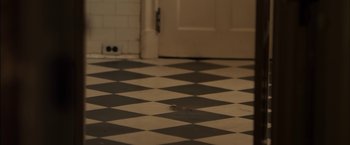 Movie still from “You're Next” (2011), directed by Adam Wingard – A black and white checkerboard floor in a kitchen; Wide shot, High angle