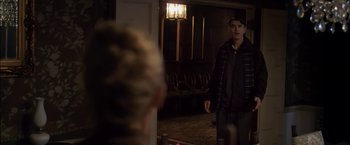 Movie still from “You're Next” (2011), directed by Adam Wingard – A man standing in front of a mirror in a room; Medium shot, Over the shoulder angle