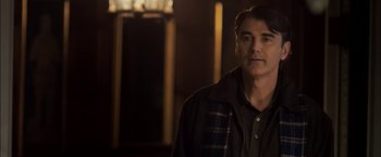 Movie still from “You're Next” (2011), directed by Adam Wingard – A person standing in a room; Medium shot, Over the shoulder angle