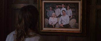 Movie still from “You're Next” (2011), directed by Adam Wingard – A woman standing in front of a framed picture; Medium shot, High angle
