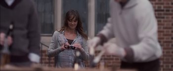 Movie still from “You're Next” (2011), directed by Adam Wingard – A woman is holding a camera and looking at a cell phone; Medium shot, Over the shoulder angle