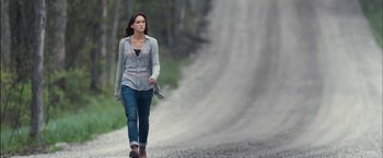 Movie still from “You're Next” (2011), directed by Adam Wingard – A woman walking down a dirt road near a waterfall; Wide shot, Over the shoulder angle