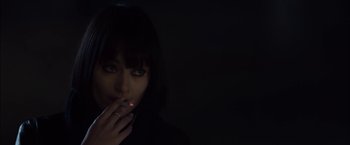 Movie still from “You're Next” (2011), directed by Adam Wingard – A woman smoking a cigarette in a dark room; Close Up shot, High angle