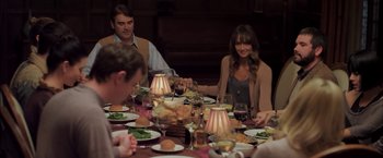Movie still from “You're Next” (2011), directed by Adam Wingard – A group of people sitting around a table with food; Medium shot, High angle