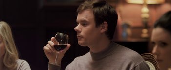 Movie still from “You're Next” (2011), directed by Adam Wingard – A man holding a glass of red wine in his hand; Close Up shot, Over the shoulder angle