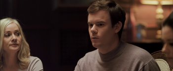 Movie still from “You're Next” (2011), directed by Adam Wingard – A young man in a sweater looking to his left; Close Up shot, Over the shoulder angle