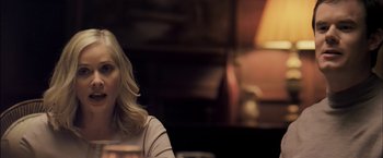 Movie still from “You're Next” (2011), directed by Adam Wingard – A woman sitting at a table in a room; Close Up shot, Over the shoulder angle