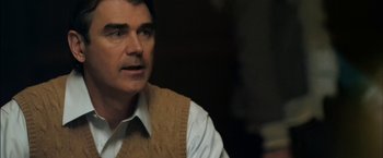 Movie still from “You're Next” (2011), directed by Adam Wingard – A person sitting in a room; Close Up shot, Over the shoulder angle