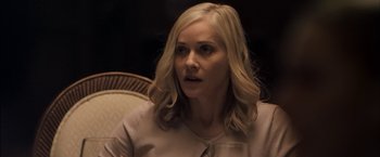 Movie still from “You're Next” (2011), directed by Adam Wingard – A woman sitting in front of a chair looking at the camera; Close Up shot, Over the shoulder angle