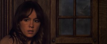 Movie still from “You're Next” (2011), directed by Adam Wingard – A woman standing in front of a wooden door; Close Up shot, Over the shoulder angle