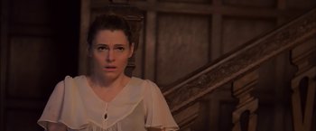 Movie still from “You're Next” (2011), directed by Adam Wingard – A woman standing in front of a wooden staircase; Close Up shot, High angle