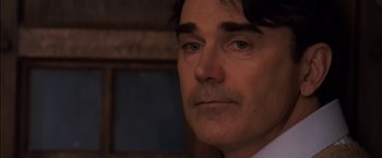 Movie still from “You're Next” (2011), directed by Adam Wingard – A person wearing a suit and tie; Close Up shot, Over the shoulder angle