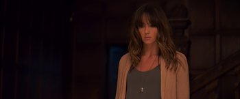 Movie still from “You're Next” (2011), directed by Adam Wingard – A woman in a gray shirt and a brown jacket; Close Up shot, Over the shoulder angle