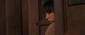 Movie still from “You're Next” (2011), directed by Adam Wingard – A woman sitting in front of an open door; Close Up shot, Over the shoulder angle