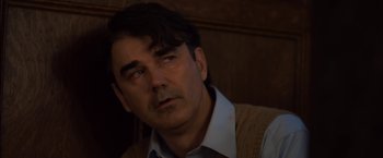 Movie still from “You're Next” (2011), directed by Adam Wingard – A person wearing a shirt and vest; Close Up shot, Over the shoulder angle