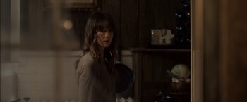 Movie still from “You're Next” (2011), directed by Adam Wingard – A woman standing in front of a stove in a kitchen; Medium shot, Low angle